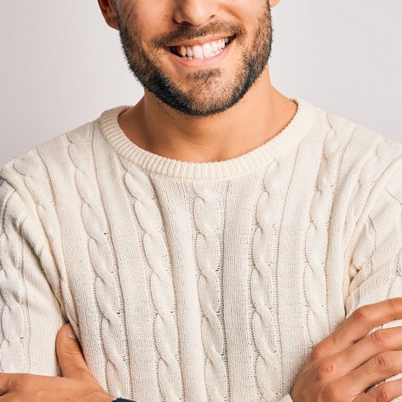 Young handsome man wearing casual sweater standing over isolated white background happy face smiling with crossed arms looking at the camera. Positive person.