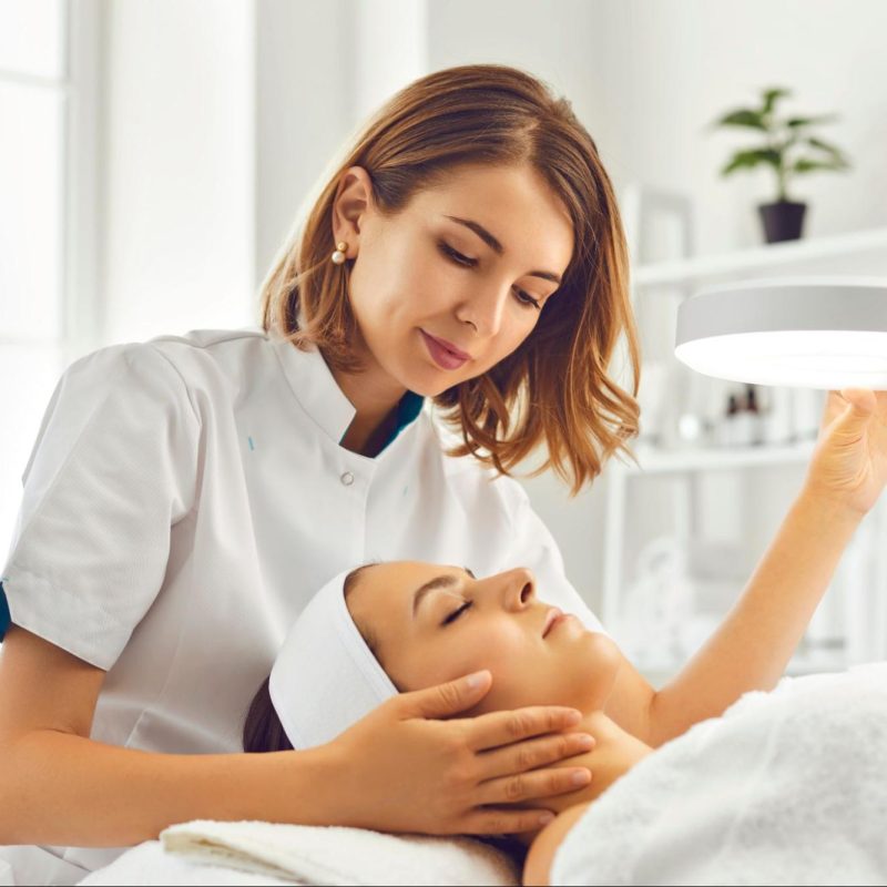 A skincare expert assessing a client’s skin type to recommend a personalized skincare treatment plan.